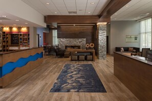 A hotel lobby with a reception desk, seating area, and a fireplace.
