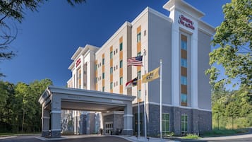 A Hampton Inn & Suites hotel with a clear sky, a welcoming entrance, and multiple flags.
