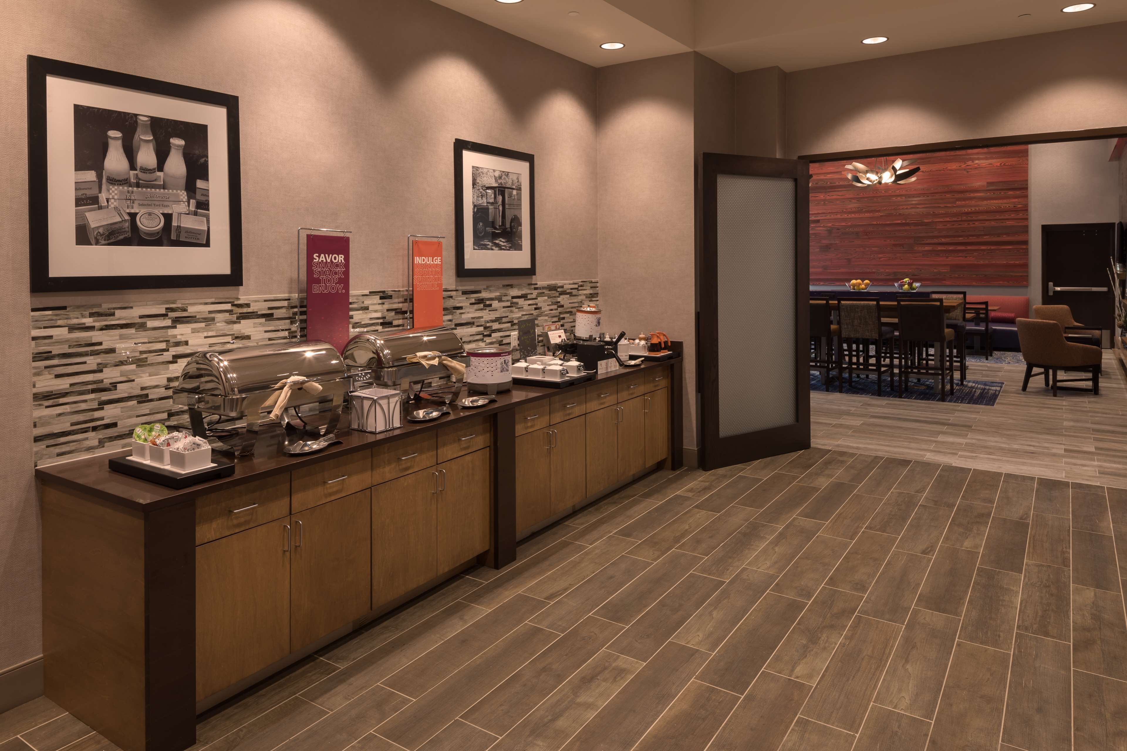 A modern kitchen with a long counter, a dining area with a table and chairs, and a wooden floor.