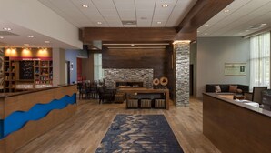 A reception area with a wooden reception desk, a fireplace, and a seating area with a blue patterned rug. - Hampton Inn & Suites Asheville Biltmore Village (Asheville)