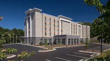 A multi-story hotel with a parking lot and landscaped areas.