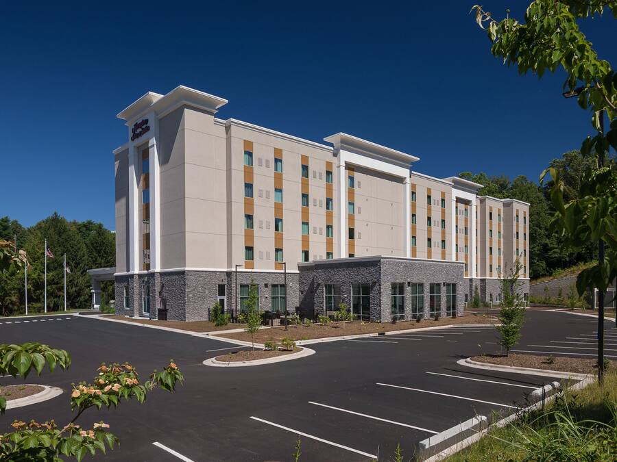 A multi-story hotel with a parking lot and landscaped areas.