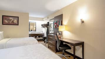 A hotel room with two beds, a desk, a chair, a desk lamp, a television, and a mirror.