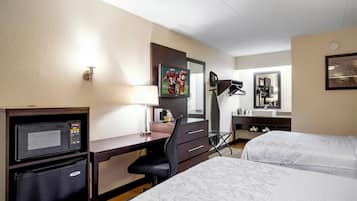 Une chambre d’hôtel équipée d’un bureau, d’une télévision, d’un lit, d’un miroir et d’une machine à café.