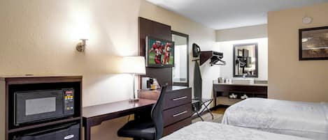 Une chambre d’hôtel équipée d’un bureau, d’une télévision, d’un lit, d’un miroir et d’une machine à café.