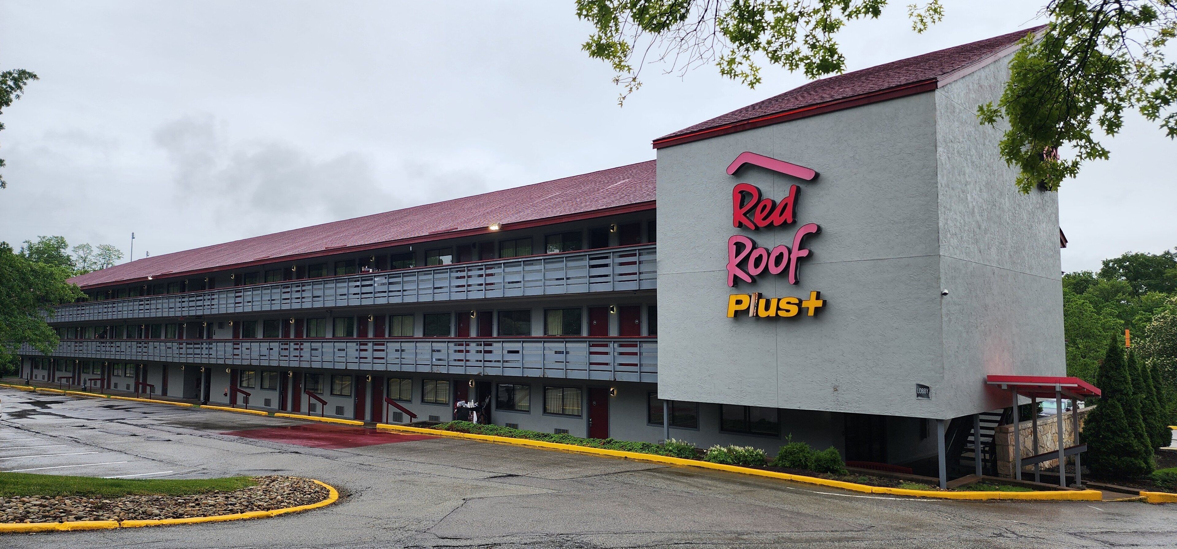 A Red Roof Plus hotel with a two-story structure, a covered parking area, and a red roof.