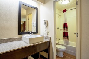 A bathroom with a sink, mirror, hairdryer, toilet, and shower curtain. - Red Roof Inn PLUS+ Pittsburgh East - Monroeville (Monroeville)