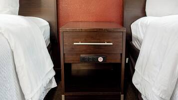 A hotel room with two single beds, a wooden nightstand with a drawer, and a red textured wall.