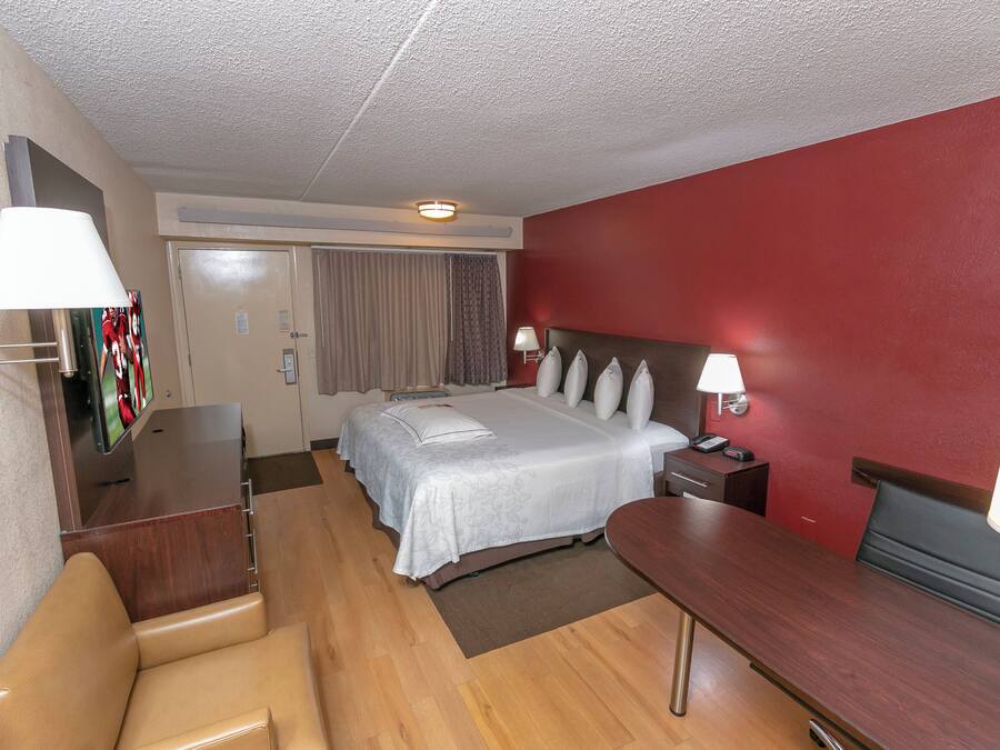 A hotel room with a bed, bedside lamps, a desk, a chair, and a telephone.