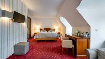 Een hotelkamer met een bed, een bureau, een stoel, een televisie en een klein voetenbankje.