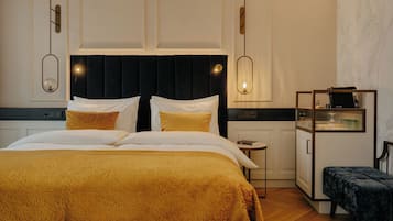 Ein Hotelzimmer mit einem großen Bett, einem Nachttisch, einer kleinen Kommode und einer Bank.