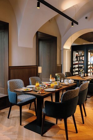 Un espace repas avec une longue table, des chaises et une variété d’aliments pour le petit-déjeuner.