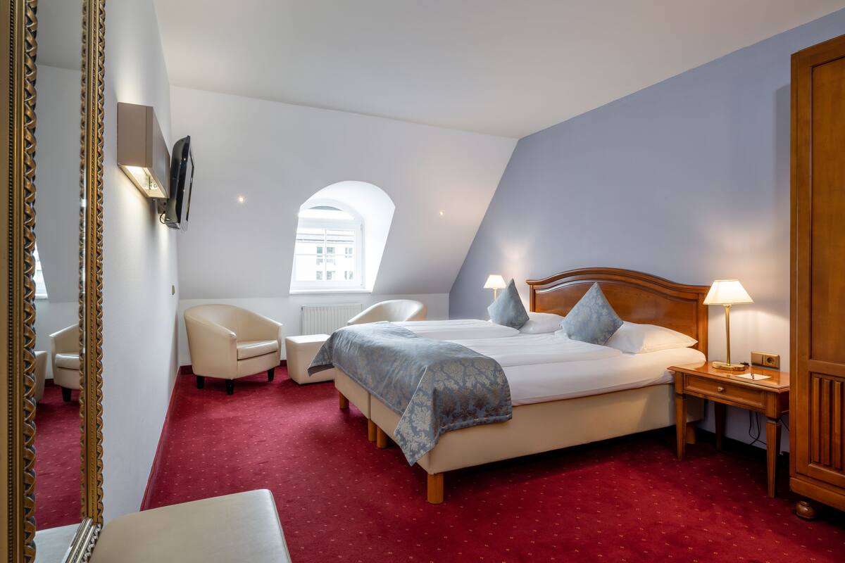 Una habitación de hotel con una cama grande, un escritorio, una silla, un televisor y una ventana con vistas a edificios.