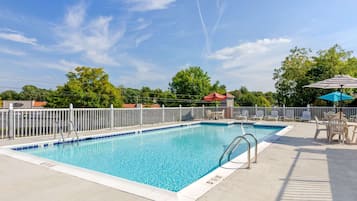 A rectangular pool with a white deck, metal railings, and a fenced area.