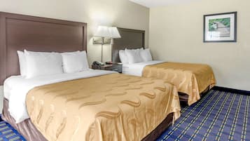 A hotel room with two beds, a nightstand, a lamp, and a framed picture on the wall.