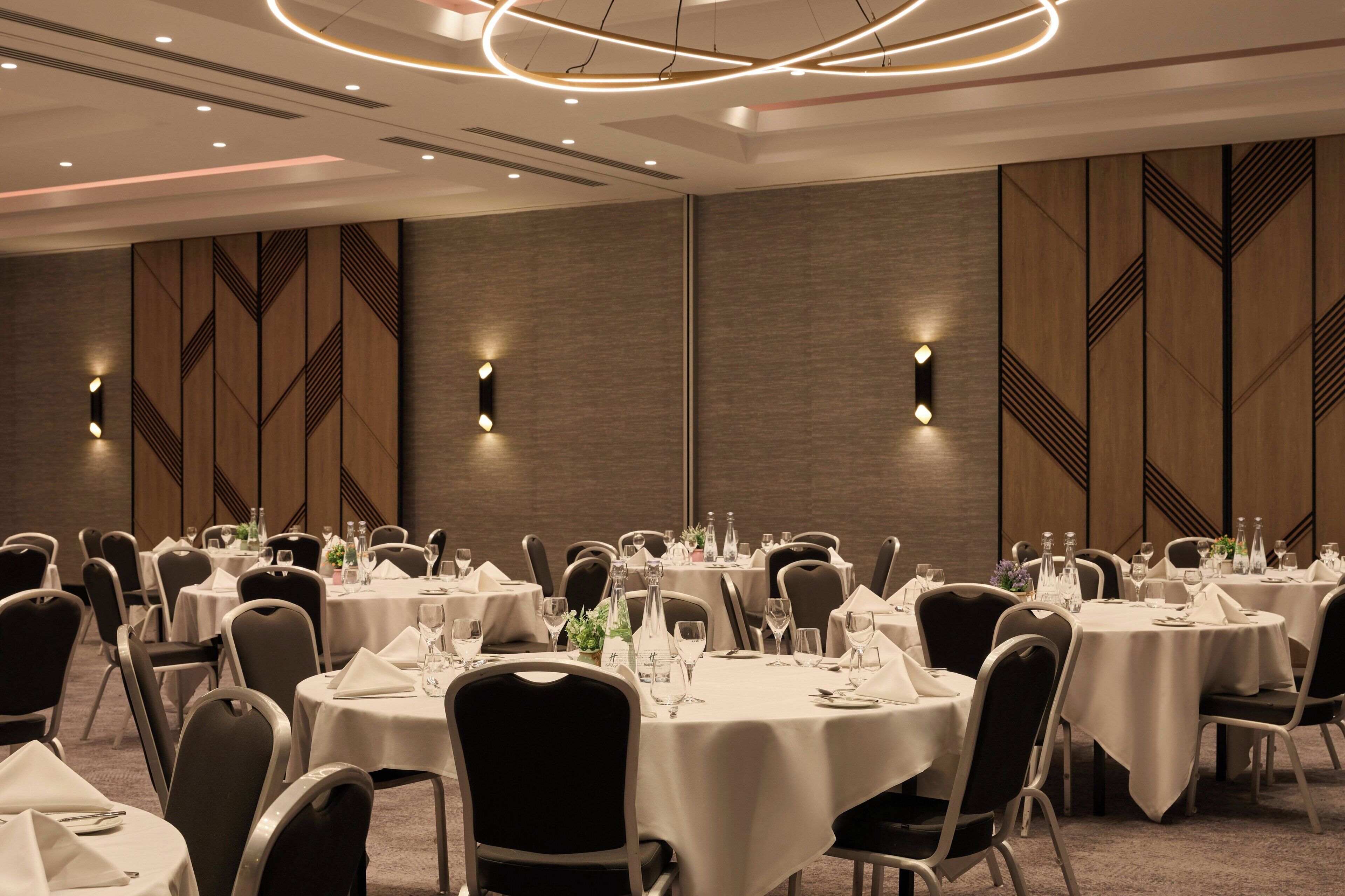 A conference room with round tables, chairs, and a modern ceiling design.