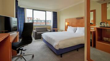 Une chambre d’hôtel équipée d’un lit, d’un bureau, d’une chaise, d’une télévision et d’une fenêtre avec des rideaux.