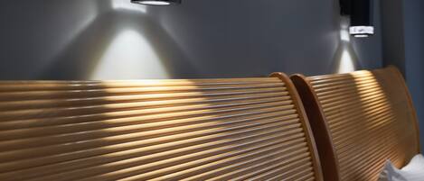 A modern room with a wooden headboard and a wall-mounted light fixture.