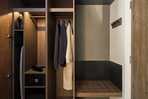 Vestidor con ropa colgada, un zapatero y una pequeña estantería con un control remoto.
