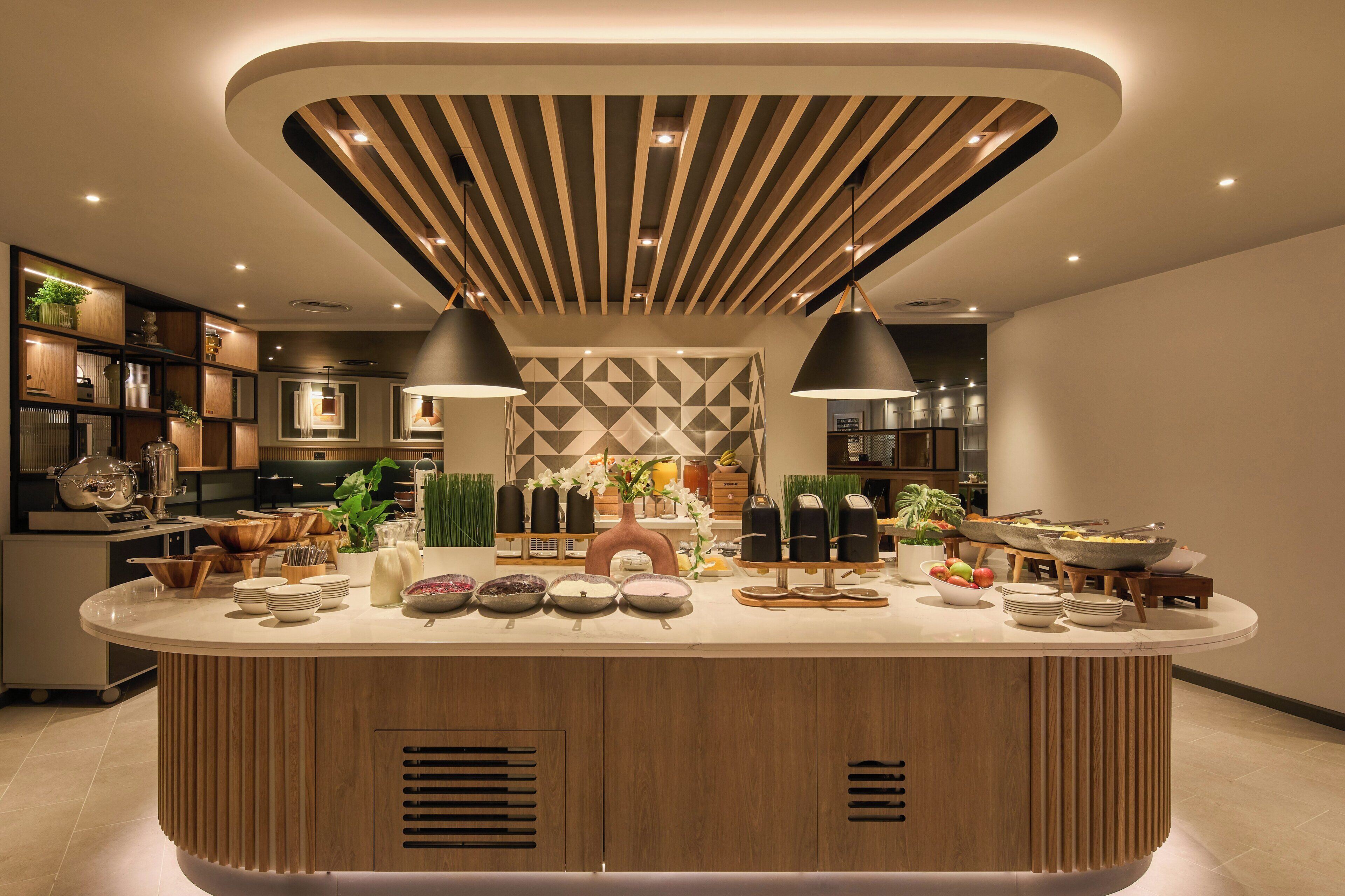 Une cuisine moderne dotée d’un îlot central, de lambris en bois et de luminaires suspendus.