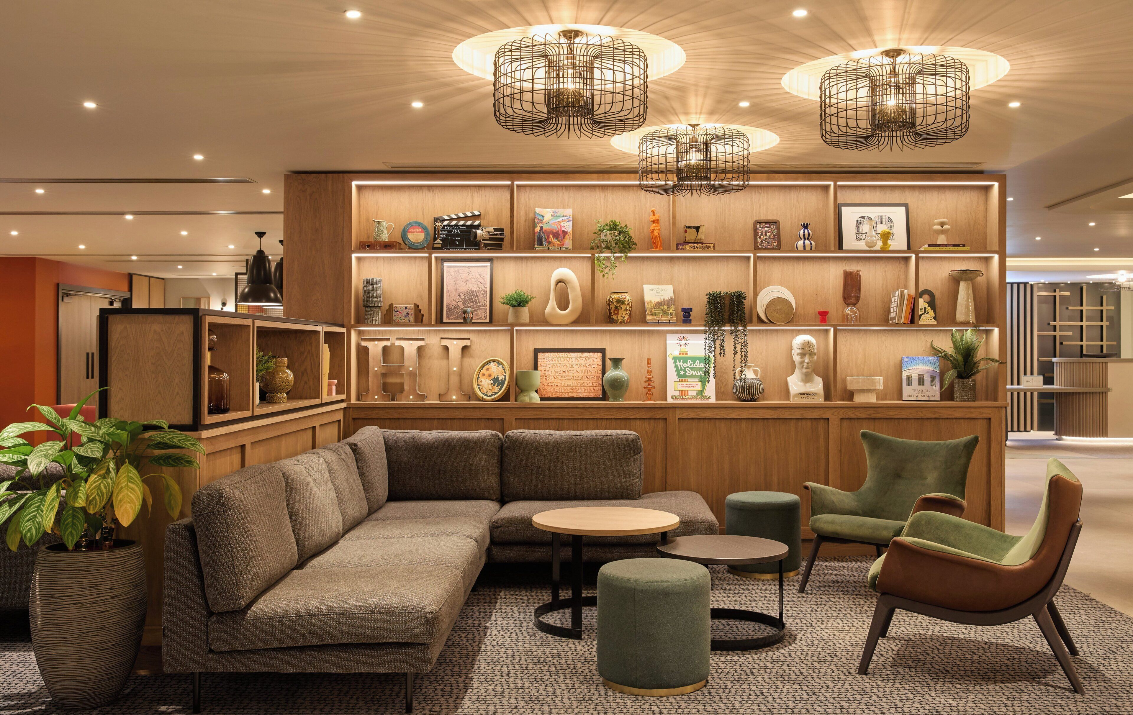 Ein moderner Lounge-Bereich mit einer Eckcouch, Sesseln, einem Couchtisch und einer Bücherwand mit Büchern und Dekoration.