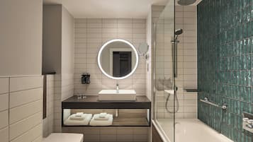 Une salle de bain moderne avec une douche à parois de verre, un lavabo blanc et un miroir doté d’un cadre circulaire.