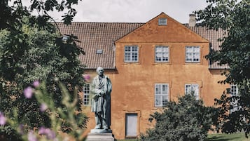 A statue in a park with a building in the background.
