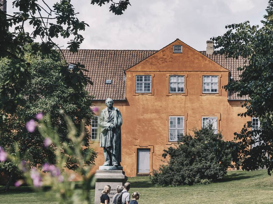 Une statue dans un parc, avec un bâtiment en arrière-plan.