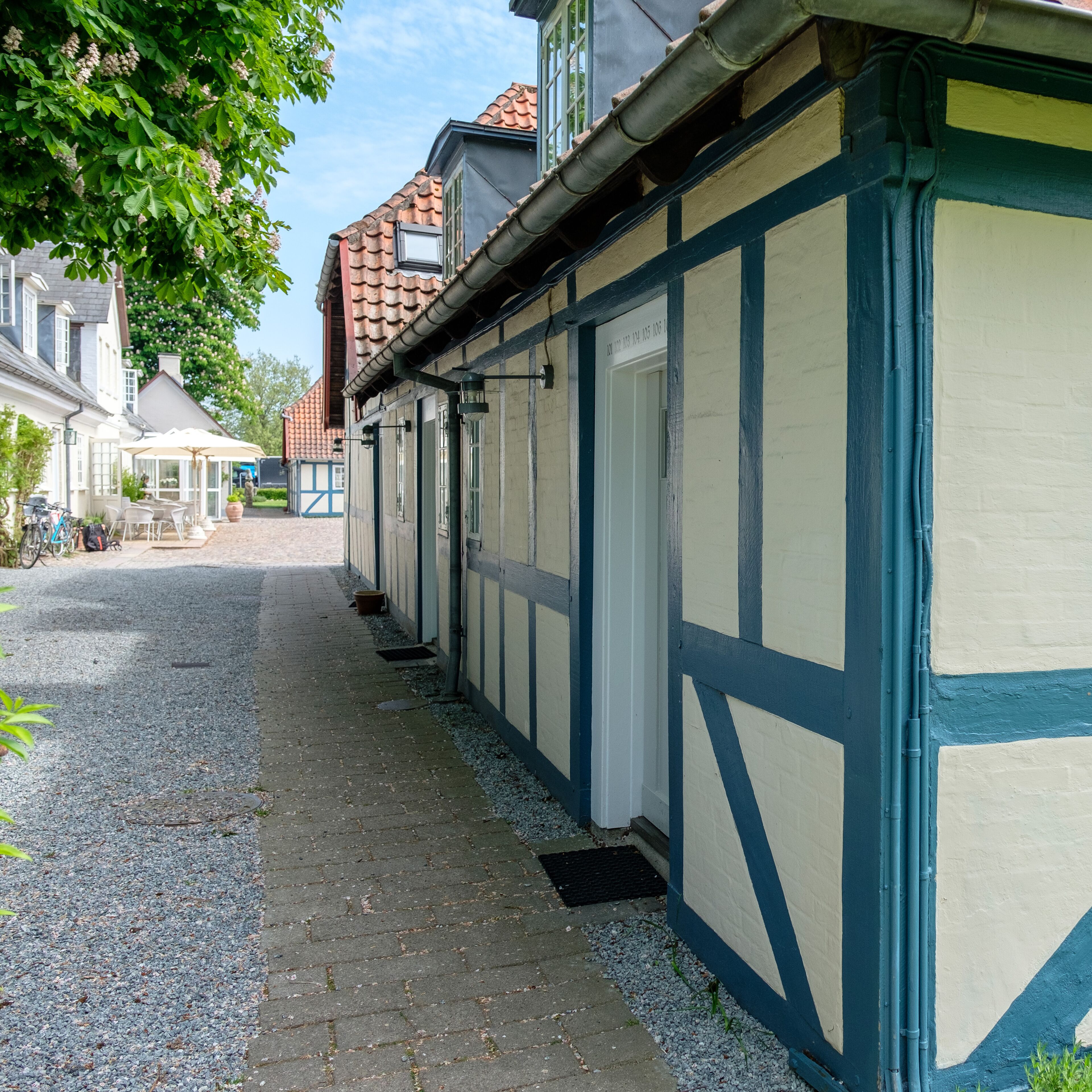 A narrow cobblestone path flanked by traditional half-timbered buildings with visible windows and doors.