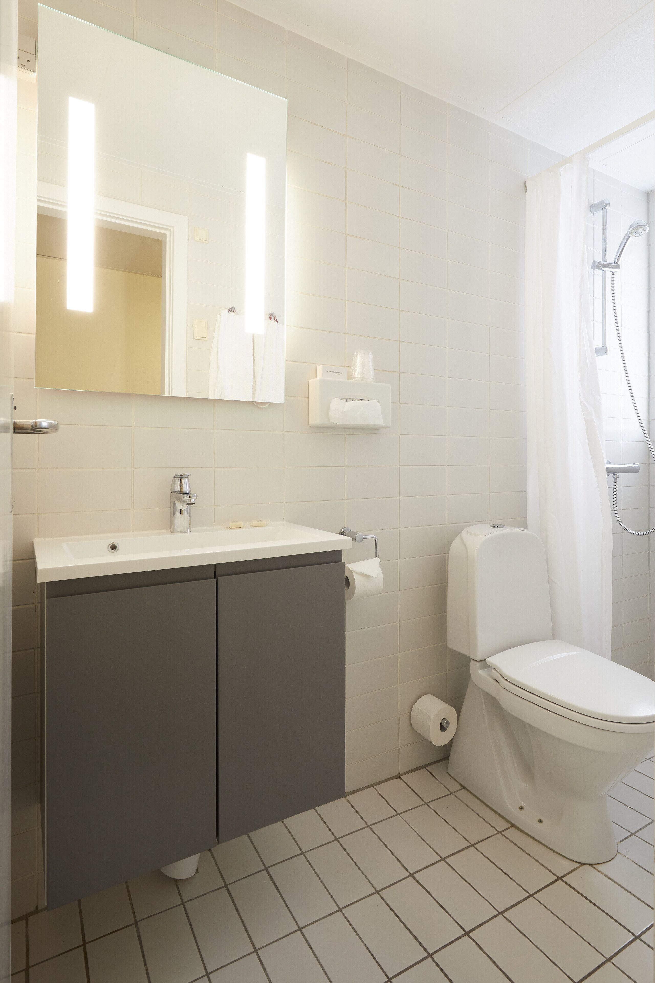 Un baño con lavamanos blanco, espejo e inodoro.