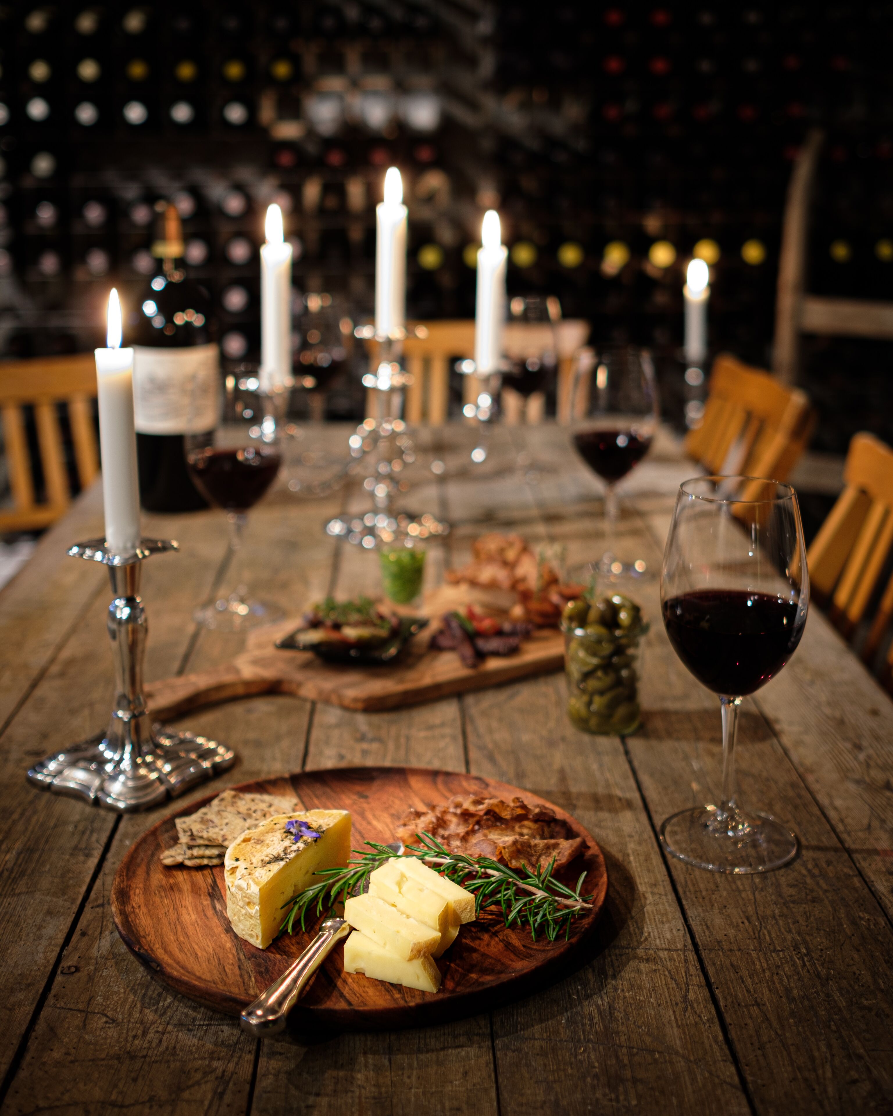 Een houten tafel met een kaasplank, kaarsen en wijnglazen.