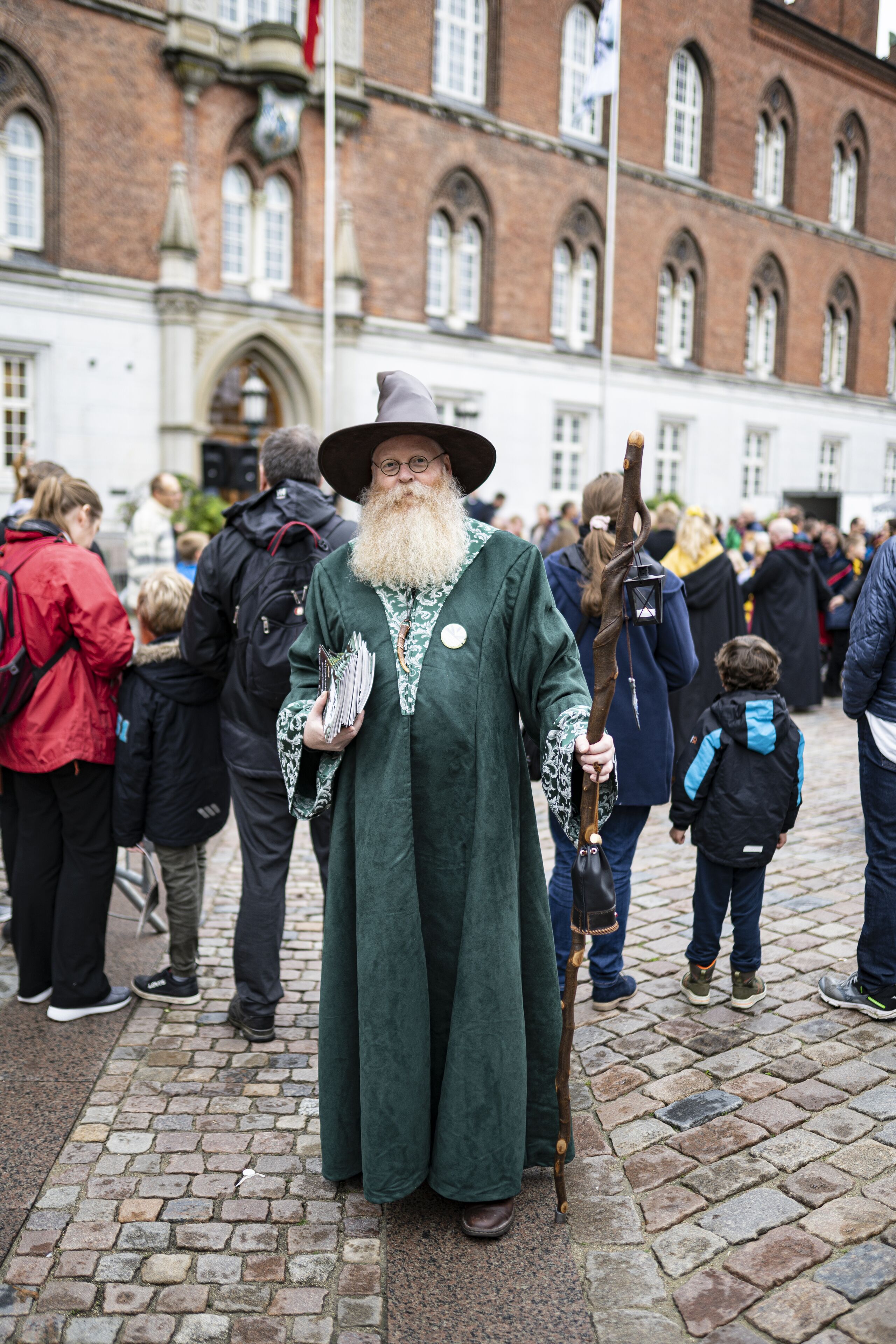 Een persoon in historisch kostuum staat op een geplaveid straatje.