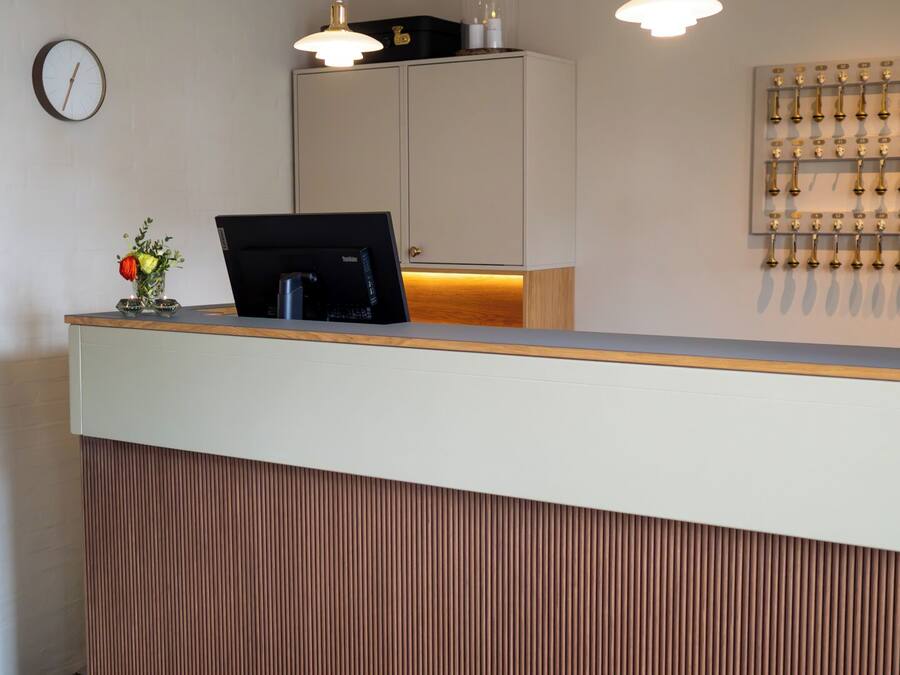 A reception desk with a laptop, a clock, and a decorative item on the wall.