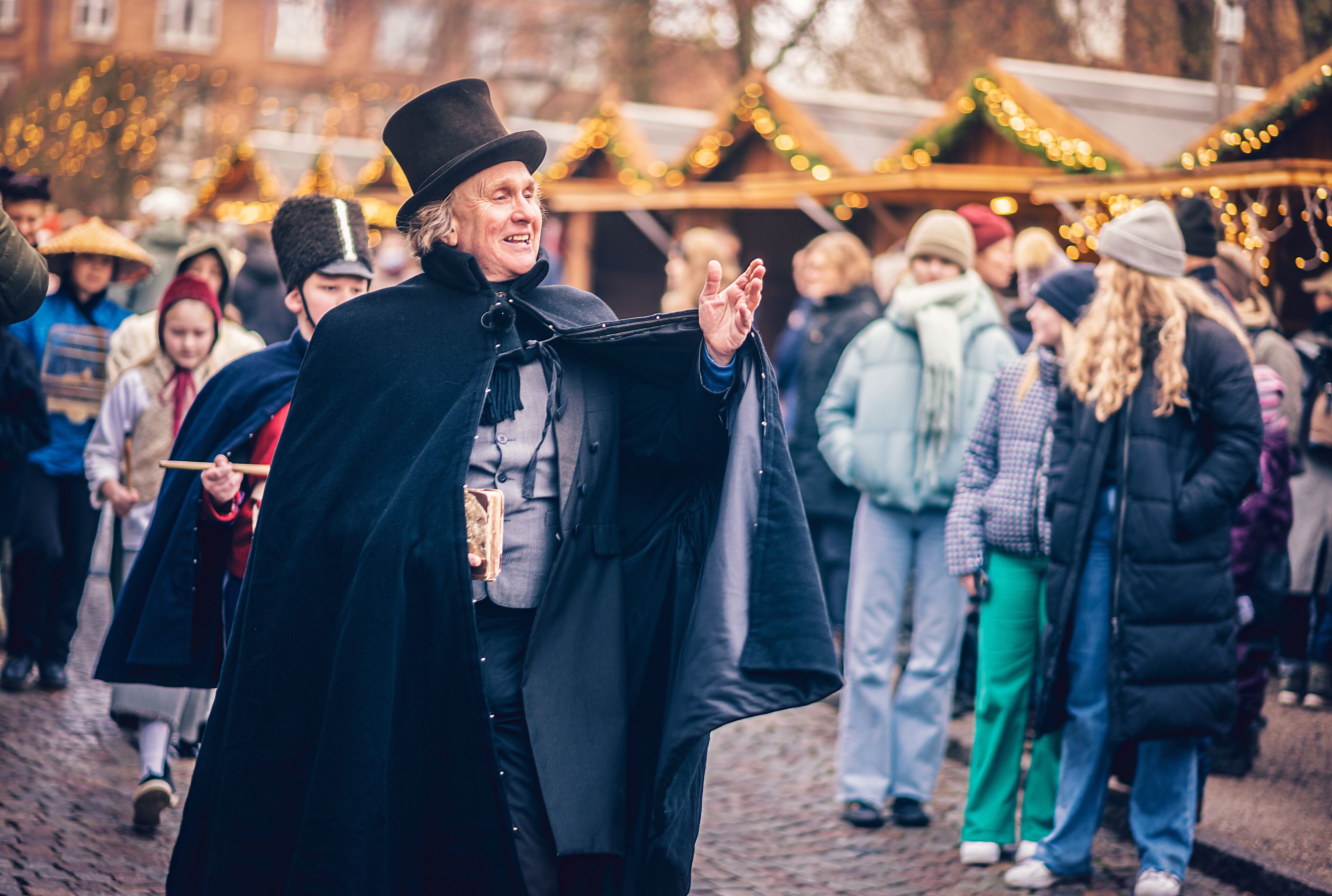 A cobblestone street with people in winter clothing, some wearing hats and coats.