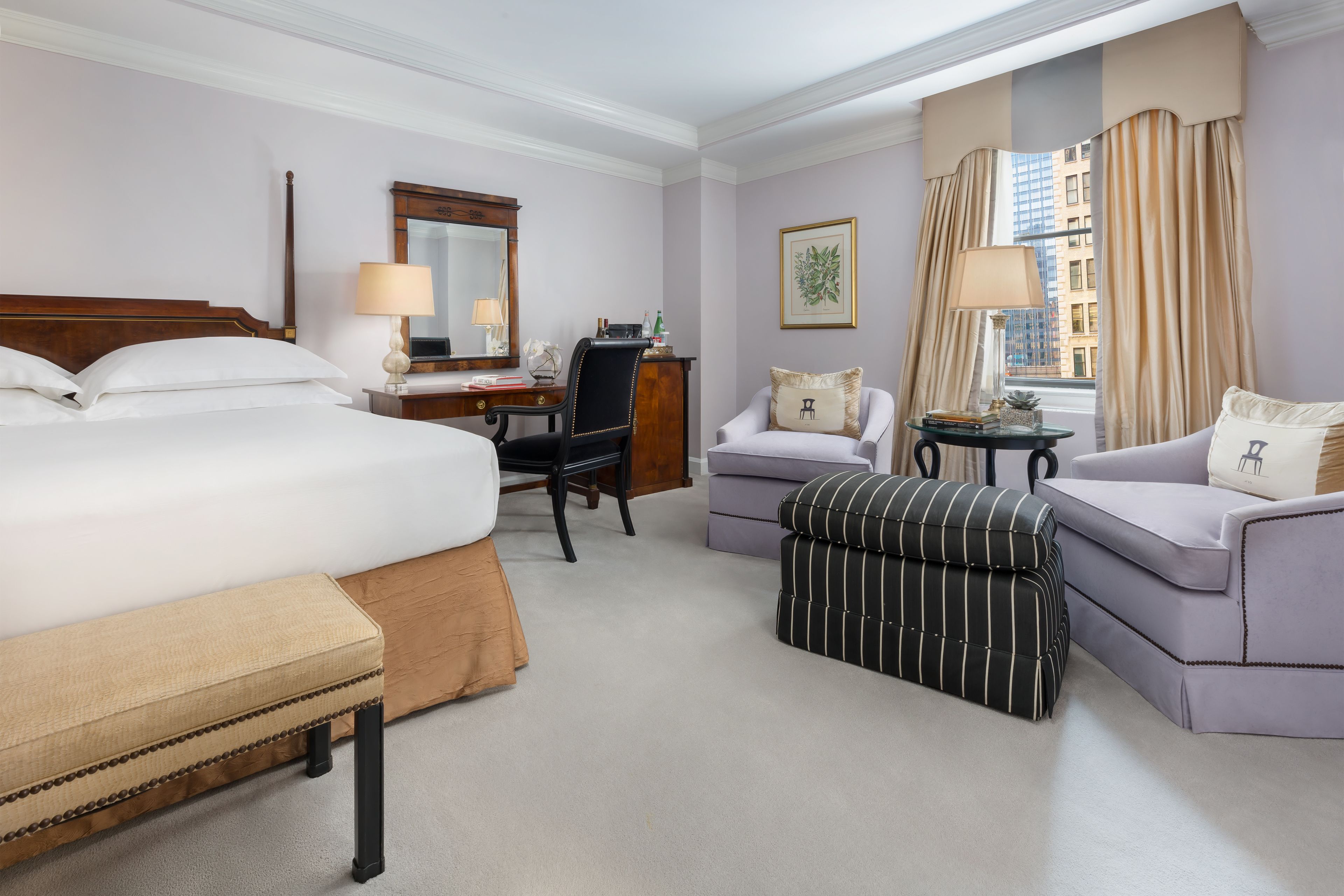Habitación de hotel con una cama grande, un escritorio, una silla, un sofá y un reposapiés.