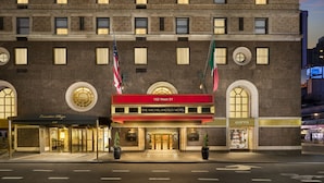 A hotel facade with a red marquee, multiple windows, and flags.
