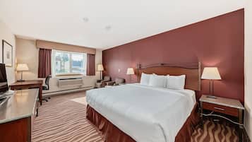 Habitación de hotel con una cama grande, un escritorio, una silla, un televisor y una ventana con cortinas.