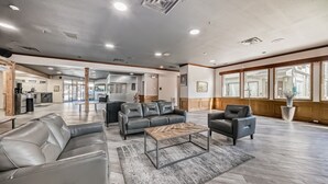 A spacious lobby with leather sofas, a coffee table, and large windows.