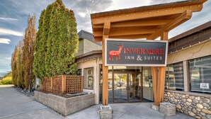 The exterior of Invermere Inn & Suites, featuring a prominent sign with a deer logo, a stone facade, and a covered entrance area.