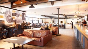 A spacious cafe with leather seating, a bar area, and a wall displaying historical photos.