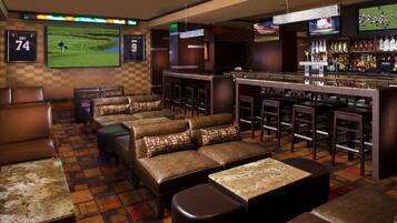 A bar area with leather seating, a bar counter, and a television screen displaying sports.