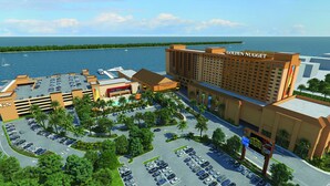 A hotel with a large parking lot, a pool area, and a view of the ocean.