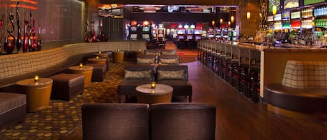 En bar med sittplatser, spelautomater och en bardisk.