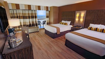 Une chambre d’hôtel avec deux lits, un bureau avec une lampe, une chaise et une vue sur la mer.