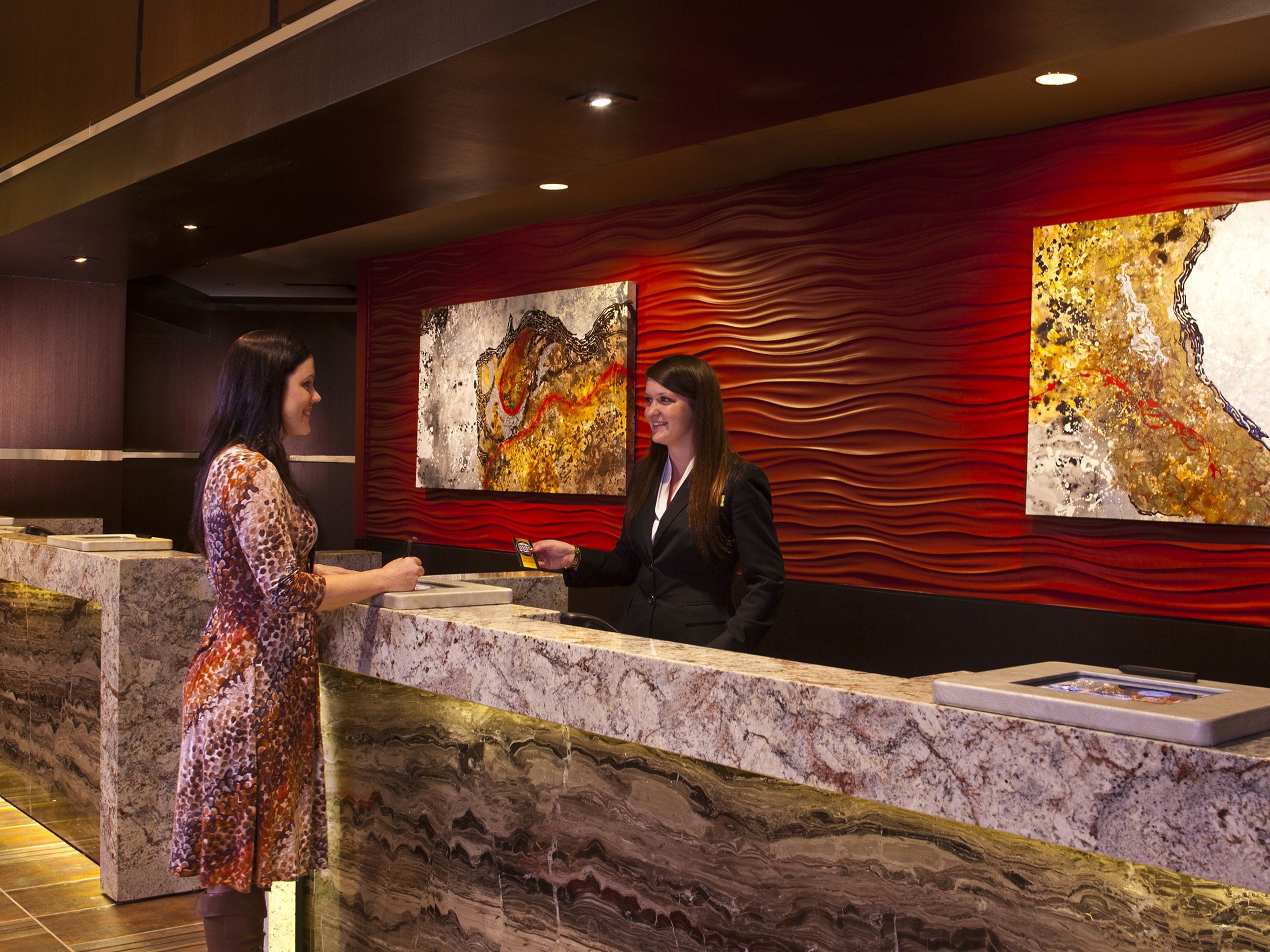 A reception desk with marble counter and artwork on the wall.