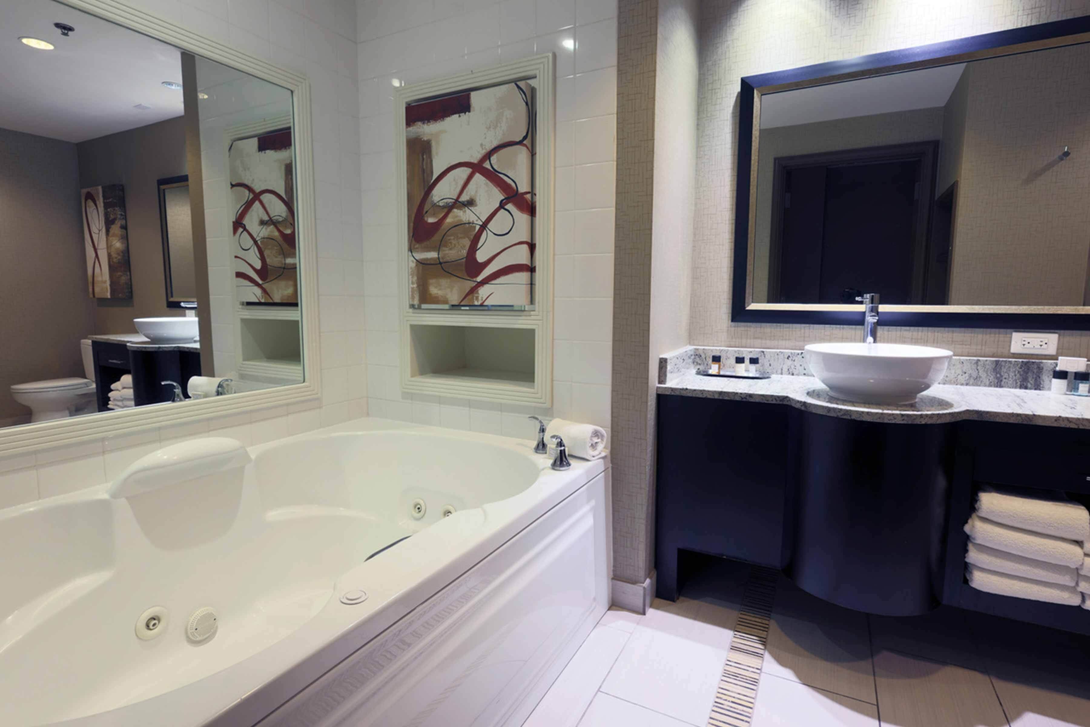 A modern bathroom with a large bathtub, a vanity with a sink, and a mirror above the vanity.