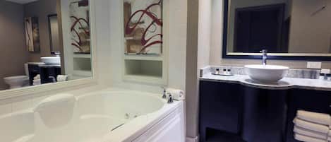 A modern bathroom with a large bathtub, a vanity with a sink, and a mirror above the vanity.