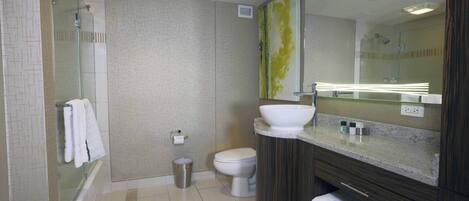 A modern bathroom with a glass-enclosed shower, a white toilet, a large mirror, and a vanity with a sink and towel rack.