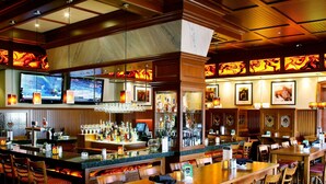 A restaurant with wooden furniture, a bar area, and multiple televisions.
