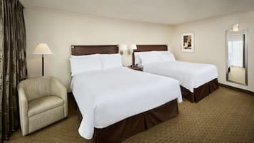 Habitación de hotel con dos camas, una silla, una lámpara, una mesita de noche y un espejo.